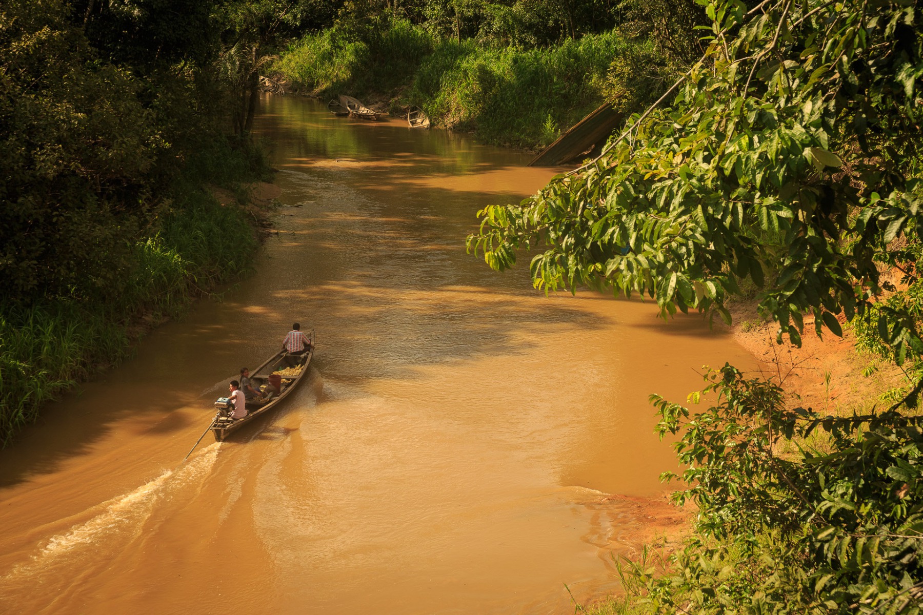 Pirogue remontant un fleuve d'ocre en Amazonie, Leticia